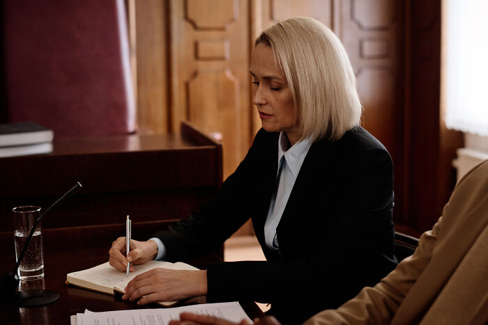 Woman in professional attire writing notes at a desk, representing professions often seen as not relationship material.