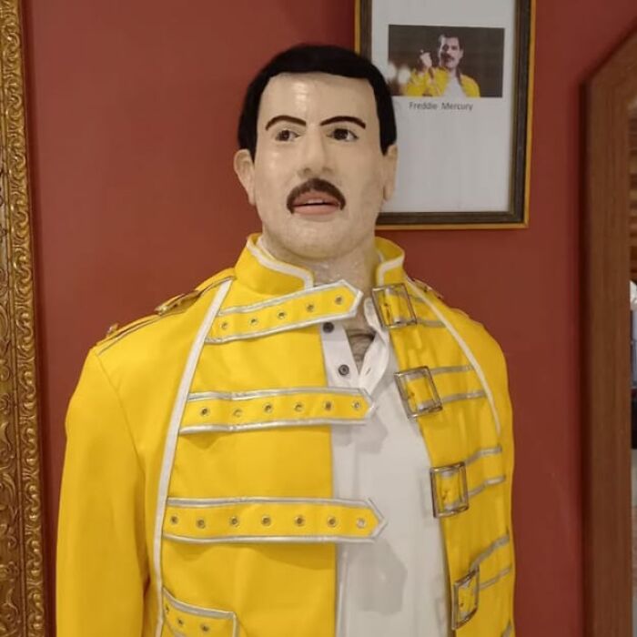 Wax sculpture of famous figure in yellow jacket, showcasing creepy and hilarious details of wax sculptures by artist.