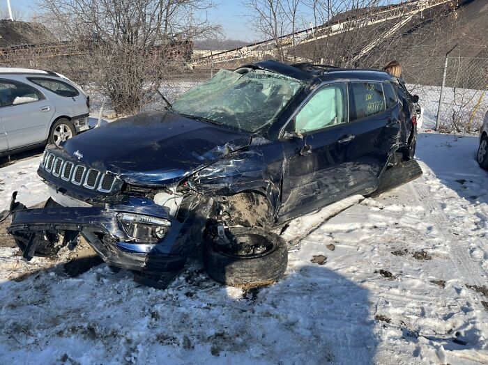 Wrecked Jeep SUV in snowy lot displaying damage from a crash, illustrating stories of people who escaped death by pure luck.