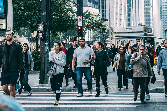 Crowd of people crossing a busy city street, illustrating unbelievable but true facts about everyday life and society.