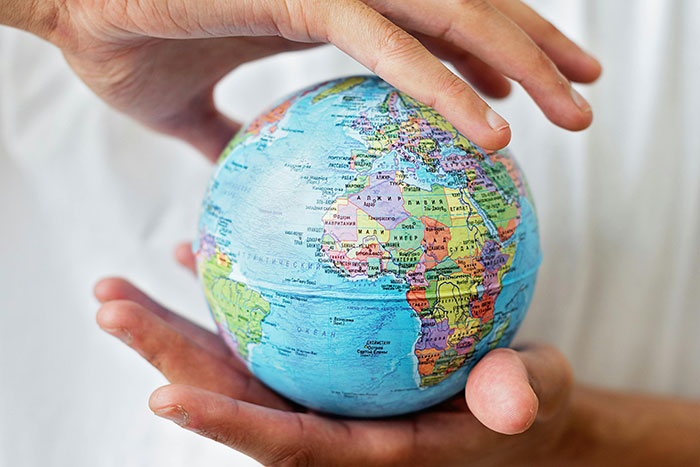 Hands gently holding a colorful globe representing unbelievable facts about the world that are actually true.