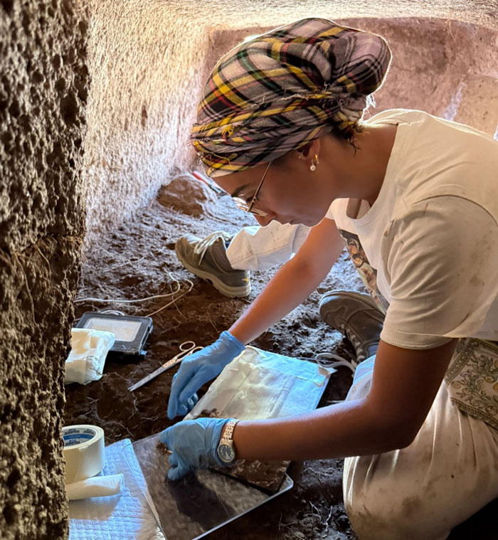 Archeologist wearing gloves carefully examining artifacts inside a 5,000-year-old fairy house on Sardinia island. Archeologist wearing gloves carefully examining artifacts inside a 5,000-year-old fairy house on Sardinia island.