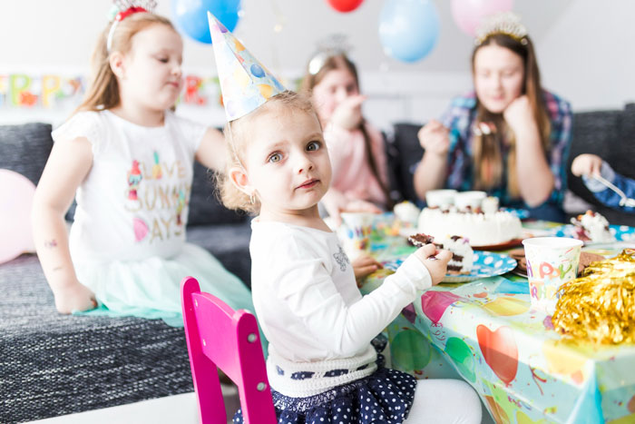Young girl in party hat sitting at decorated table with cake, illustrating family event where lady stands up for cousin's wife against rude hubby.