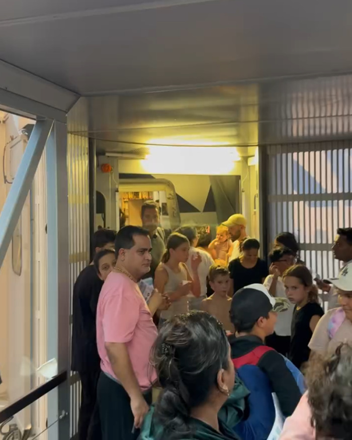Passengers crowded in a Paris flight boarding area, showing chaos and distress amid dangerous heat with an infant present.