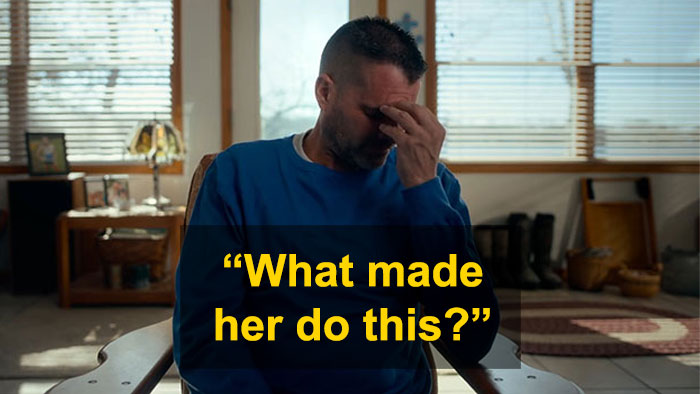 Man in blue shirt sitting indoors, holding his forehead in distress, reflecting a devastated reaction to bullying.