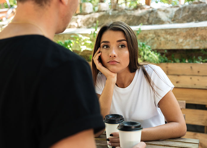 Couple having a serious conversation outdoors, woman looking concerned while man talks about late brother tattoo issue. Couple having a serious conversation outdoors, woman looking concerned while man talks about late brother tattoo issue.