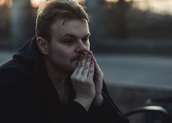 Man looking thoughtful and upset outdoors at dusk, reflecting on breaking up with fiancée over tattoo of late brother. Man looking thoughtful and upset outdoors at dusk, reflecting on breaking up with fiancée over tattoo of late brother.
