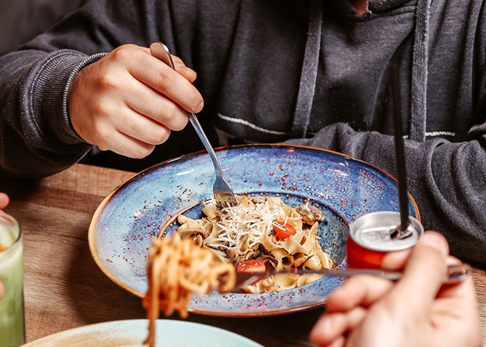Man eating pasta at a table with others, illustrating a casual meal related to man breaking up with fiancée news. Man eating pasta at a table with others, illustrating a casual meal related to man breaking up with fiancée news.