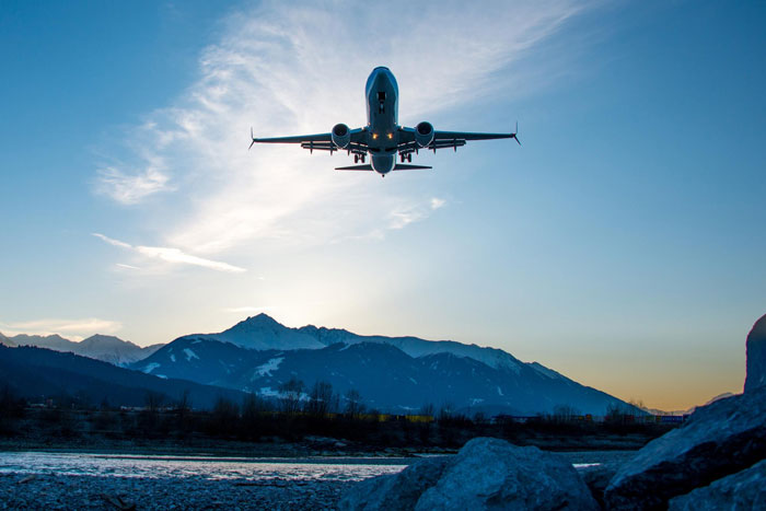 Airplane flying over mountains at sunset, illustrating a woman’s first ever first class flight experience disrupted. Airplane flying over mountains at sunset, illustrating a woman’s first ever first class flight experience disrupted.