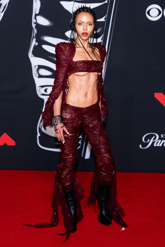 Model wearing a dark red avant-garde outfit on the red carpet showcasing worst dressed stars at the 2025 Video Music Awards.