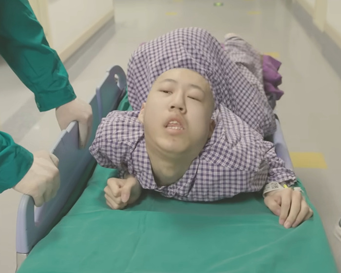 Young boy with rare condition bent at 180 degrees lying on hospital bed receiving medical care