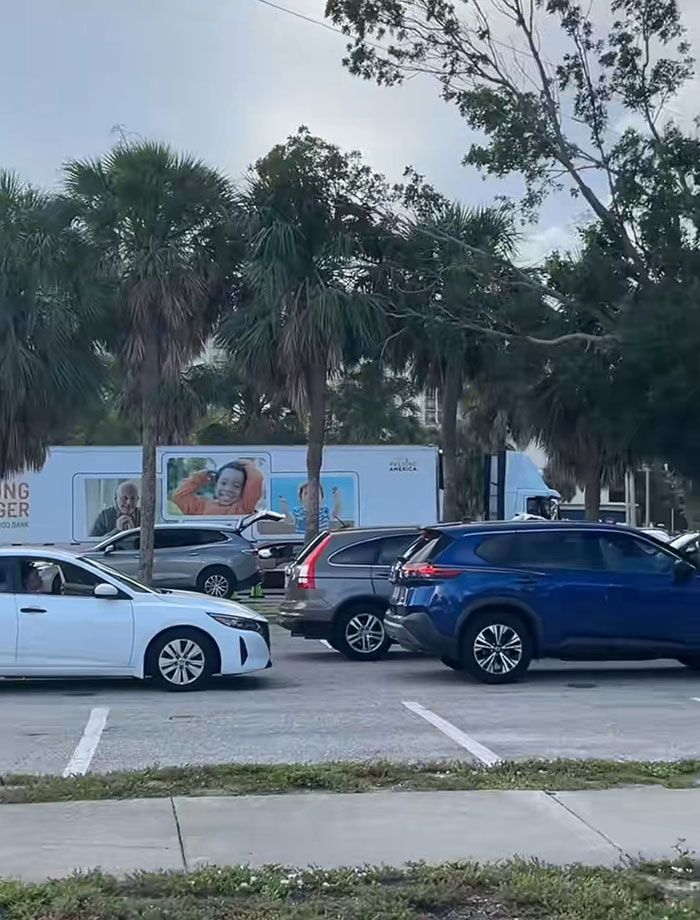 Cars lined up in a food bank parking lot in the USA, illustrating the concept of the richest poor people receiving aid.