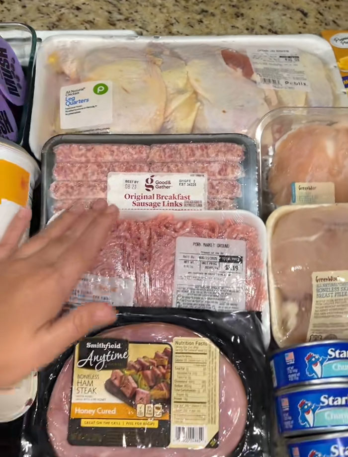 Assorted packaged meats and tuna cans on a counter showing food items from a USA food bank donation.