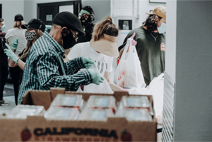 People wearing masks and gloves collecting food at a food bank, highlighting USA richest poor people assistance.