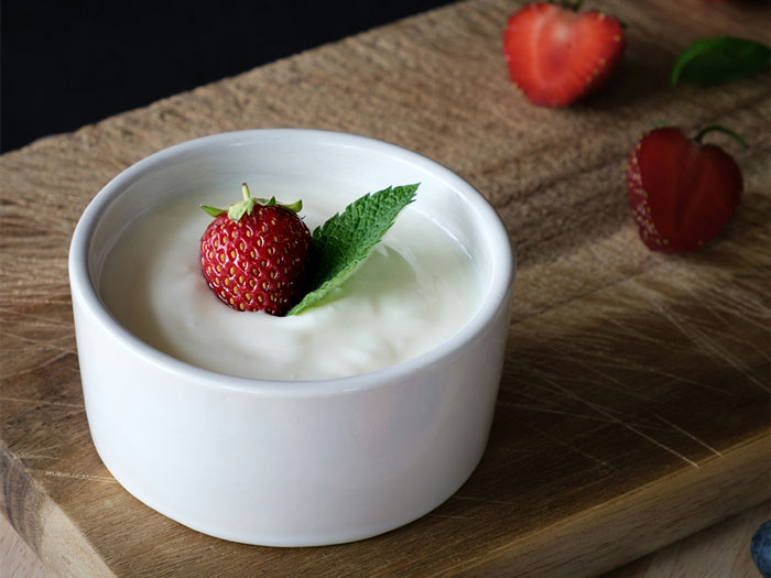 Small white bowl of creamy yogurt topped with a strawberry and mint leaf, highlighting supermarket products that trick shoppers.
