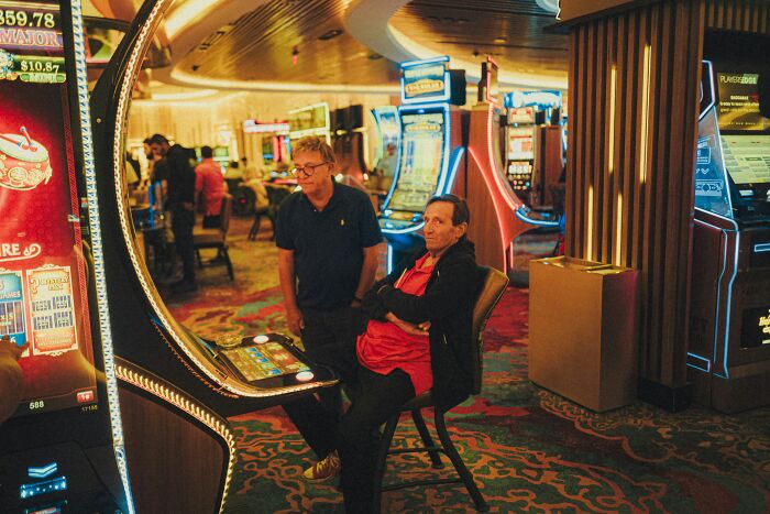Two men in a casino near slot machines, illustrating suspicion around professions like butcher and gravedigger combined.