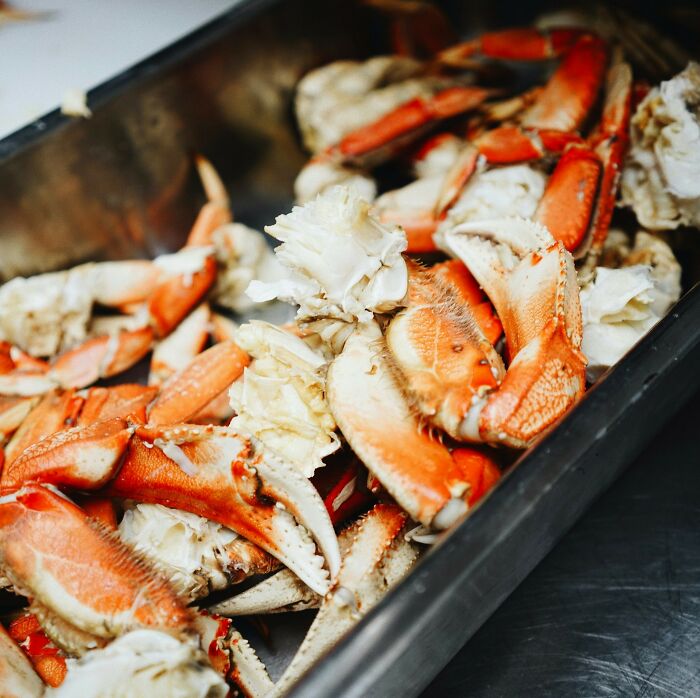 Cooked crab claws in a metal tray, illustrating a seafood dish with vibrant orange and white colors.