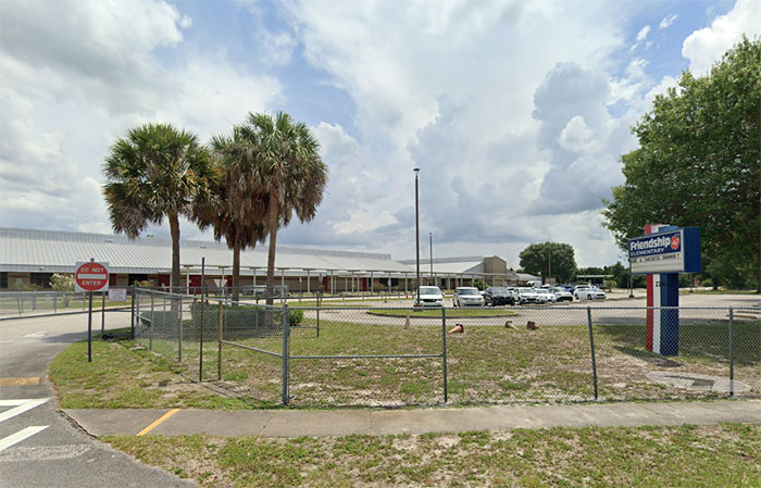 School building with parking lot and palm trees under cloudy sky, related to mothers turning in children to police.