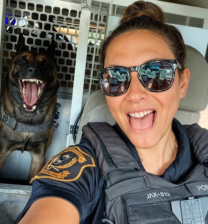 Woman in uniform smiling with a happy dog in the background, showcasing fun with animals and wholesome moments.