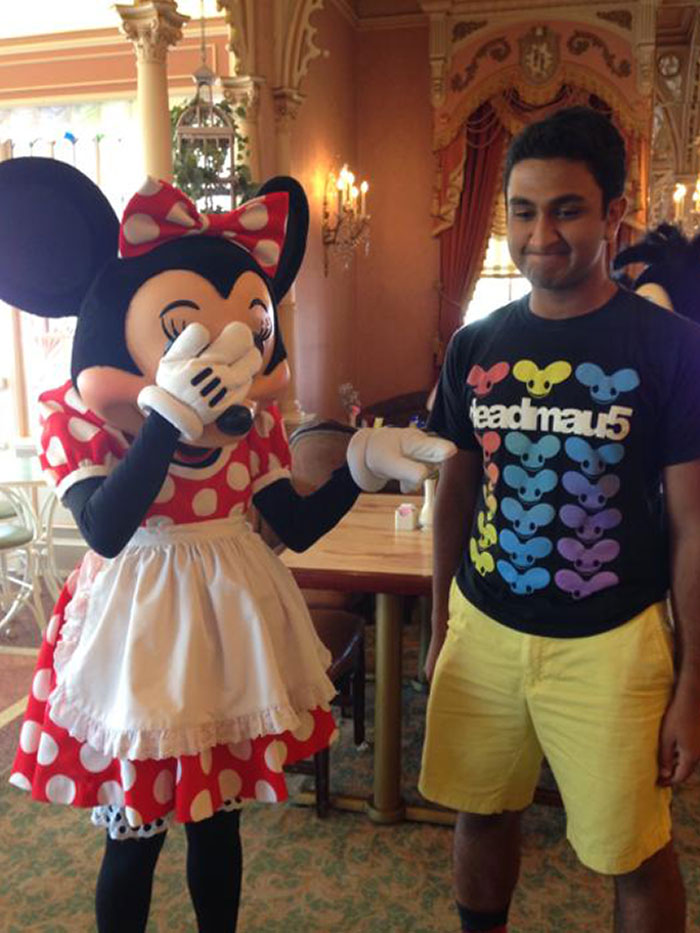 Man posing with Minnie Mouse character in colorful setting, one of the best photos brought home after an amusement park trip
