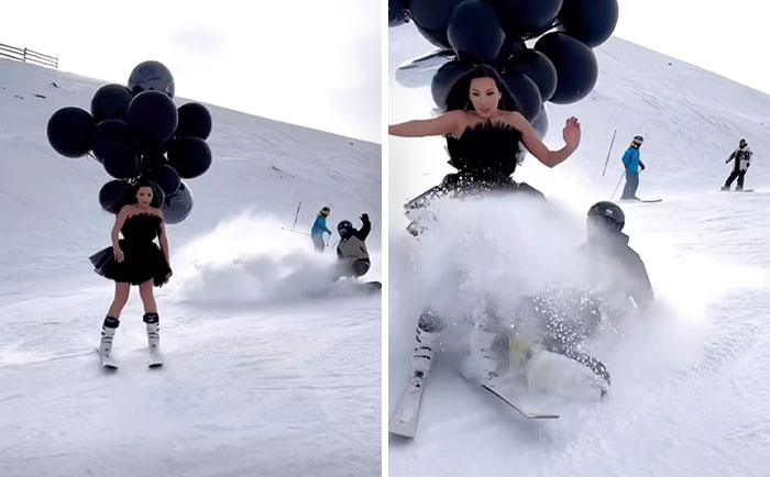 Influencer wearing black dress and balloons skiing on snow, causing a skier to fall behind with powder flying.