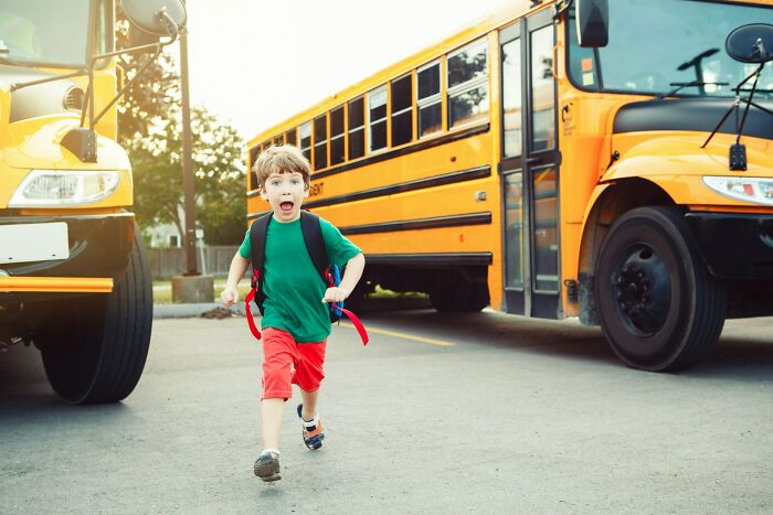 Young boy running near yellow school buses outdoors, capturing the energy of travel amid complaints about Bahamas trips.