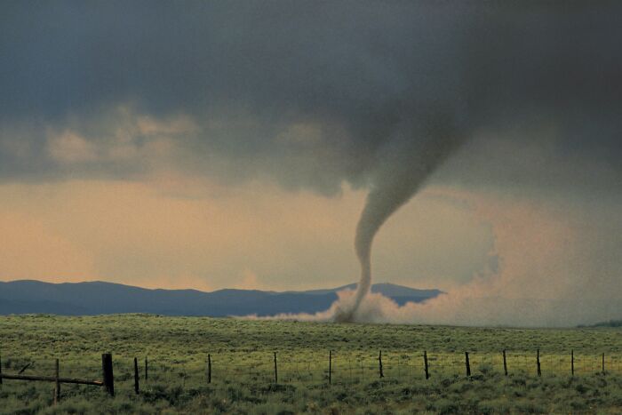 Tornado twisting through a rural landscape symbolizing sudden events causing people to lose all their savings.