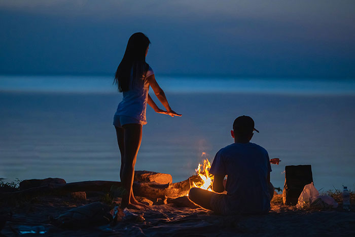 Couple by a campfire at night with man considering woman his girlfriend after one date and giving anniversary gift.