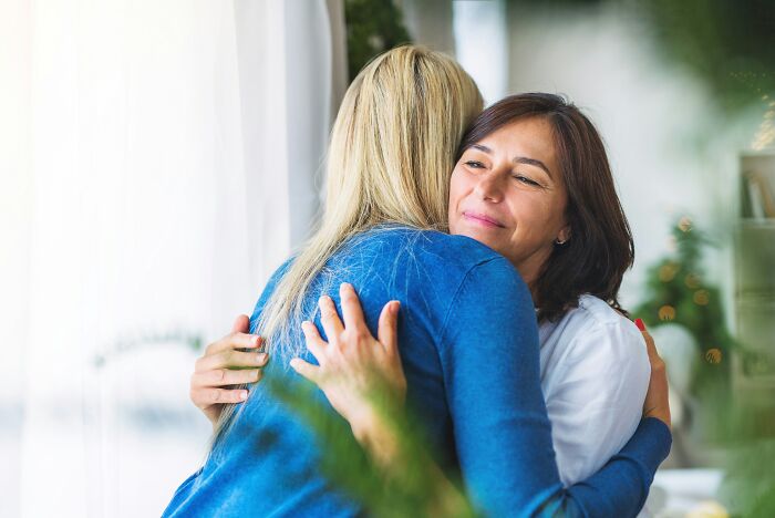Two women hugging warmly in a bright room, sharing a moment of trust and things people never admit in real life.