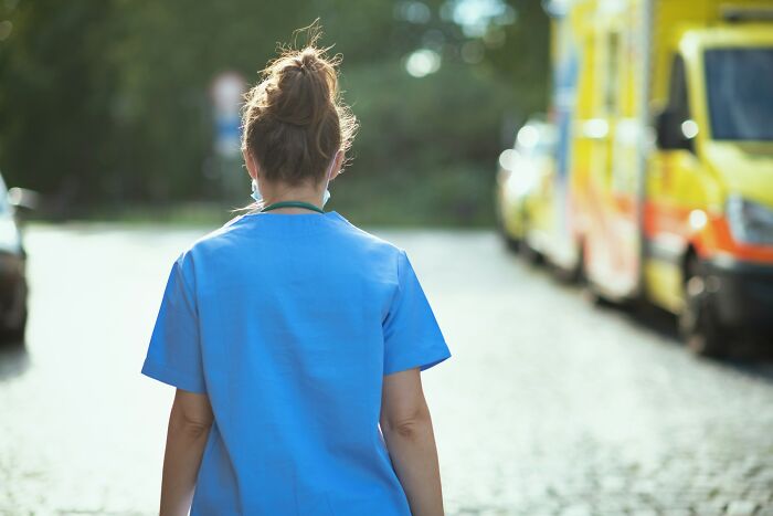 Nurse in blue scrubs walking outside near ambulances, highlighting patients who defied medical odds according to doctors.