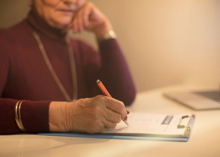 Elderly person writing on a clipboard, illustrating people sharing things they would never admit in real life.