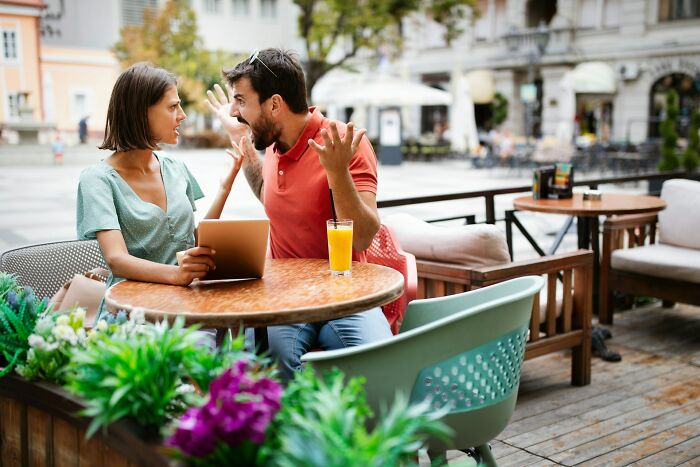 Couple having a heated argument at an outdoor cafe, illustrating crazy stories servers overheard about relationships.