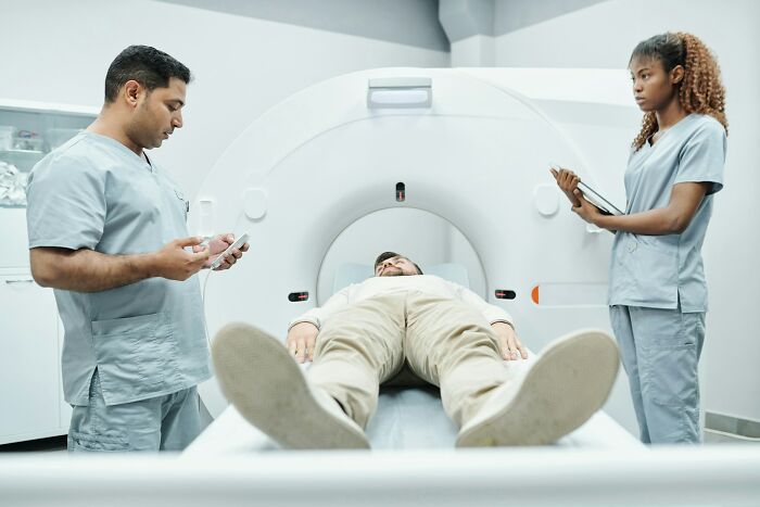 Doctors examining a patient with a rare disease during a medical scan in a clinical setting with advanced equipment.