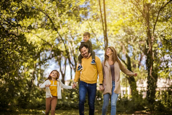 Happy family walking in park on a sunny day, illustrating men in happy marriages and strong relationship tips.