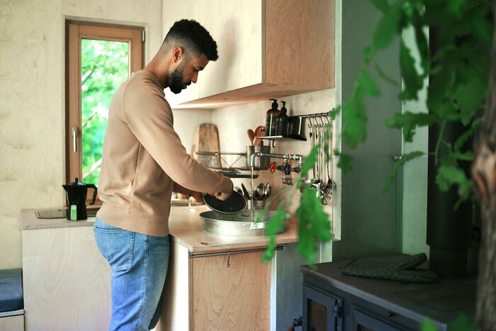Man in casual clothes preparing food in kitchen, representing men in happy marriages sharing relationship tips.