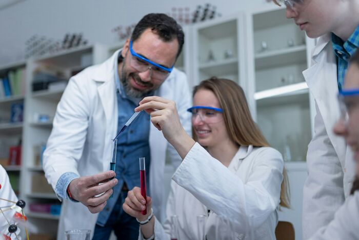 Scientists in lab coats and safety glasses handling test tubes in a laboratory setting, illustrating suspicious professions concept.
