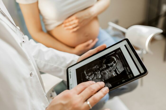 Doctor showing a pregnant woman ultrasound images on a tablet, illustrating prenatal care and medical examination.