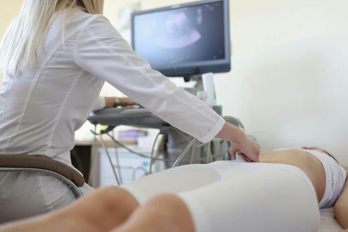 Doctor performing an ultrasound on a young woman experiencing delayed period for unexpected diagnosis in a clinical setting
