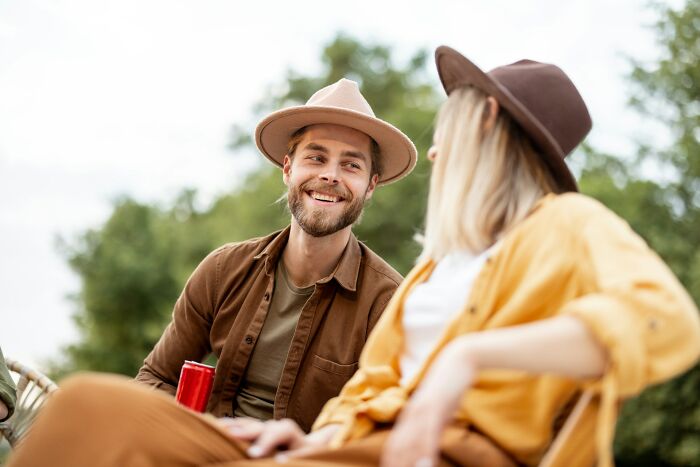 Two men wearing hats smiling and chatting outdoors, representing men in happy marriages sharing relationship tips.