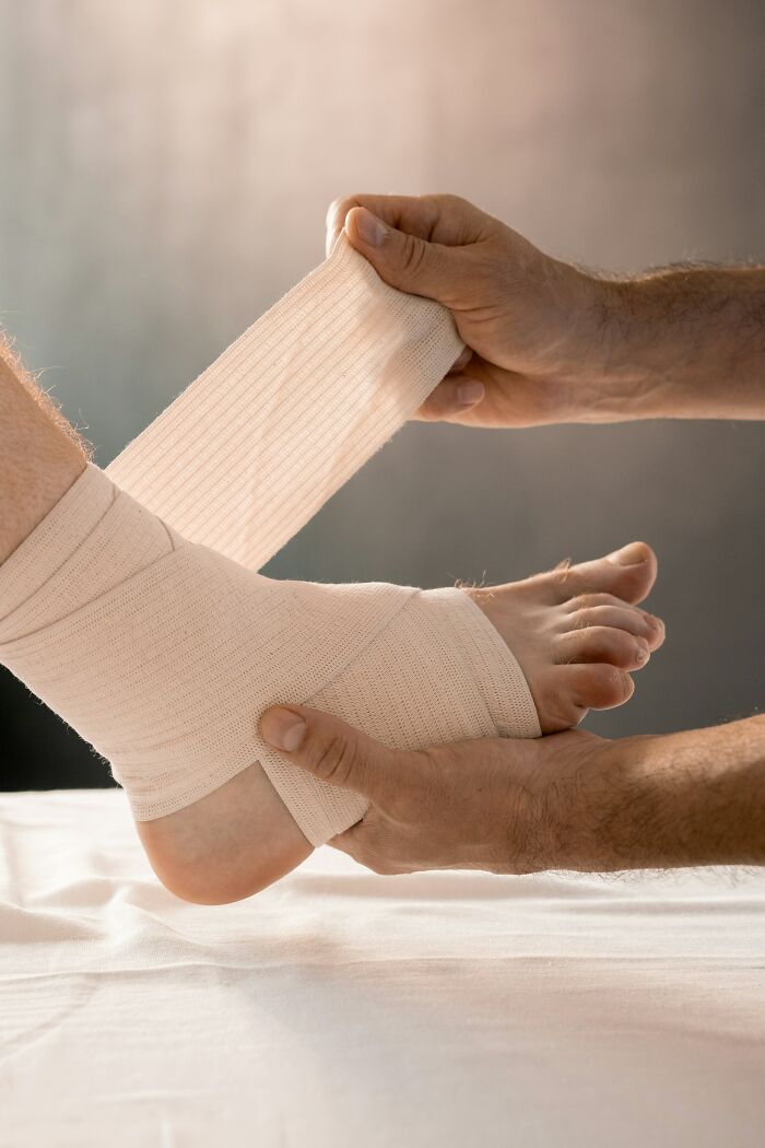 A medical professional wrapping a patient's ankle with a bandage, showing patients who defied medical odds.