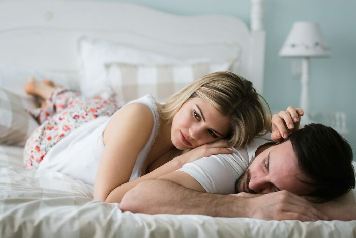 Couple lying on bed looking distant from each other, illustrating signs a relationship isn’t going to last.