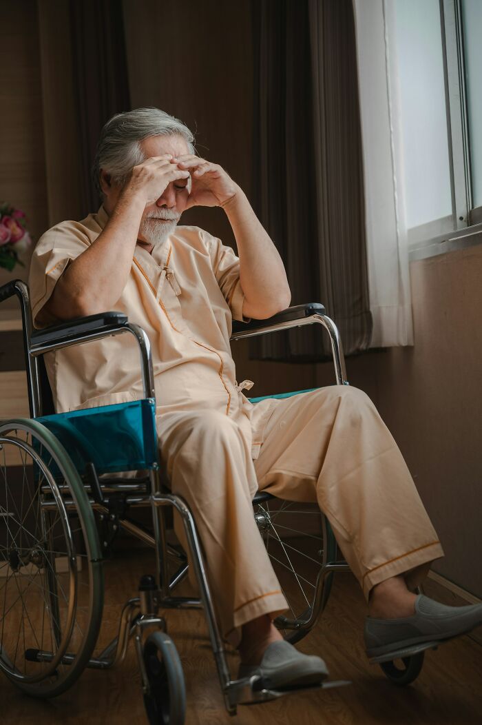Elderly man looking distressed in wheelchair by window, reflecting themes of unusual ways people died.
