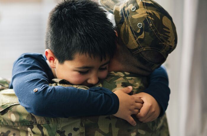 Child hugging a person in military uniform, illustrating one of the professions people believe are not relationship material.