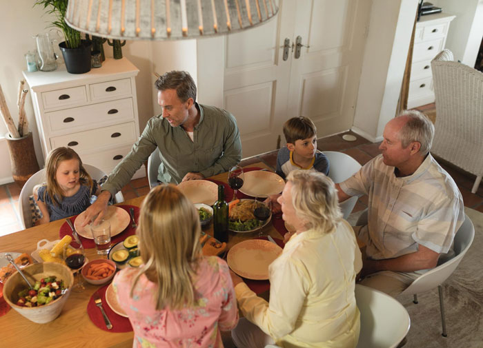 Family gathered around dining table sharing a meal, illustrating a man pranking to support autistic sister and relationship objections.