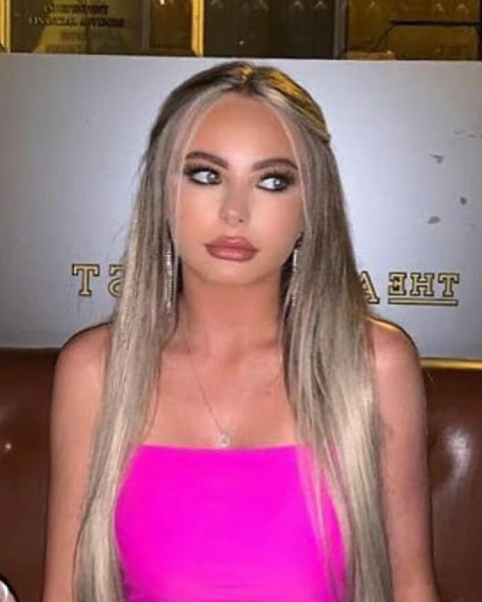 Glamorous law student with long blonde hair and pink top looking to the side in an indoor setting.