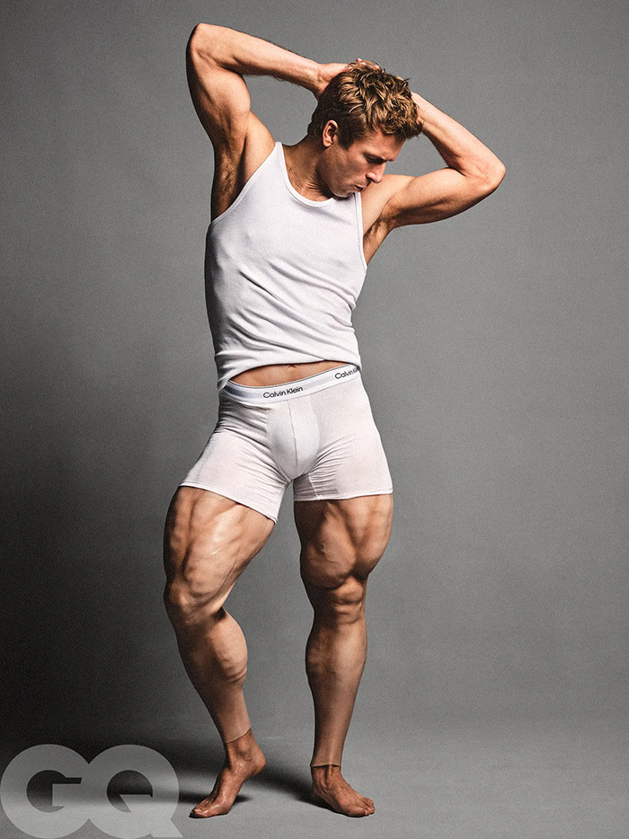 Glen Powell posing in white Calvin Klein outfit, showcasing muscular legs and toned arms in a GQ photoshoot. Glen Powell posing in white Calvin Klein outfit, showcasing muscular legs and toned arms in a GQ photoshoot.