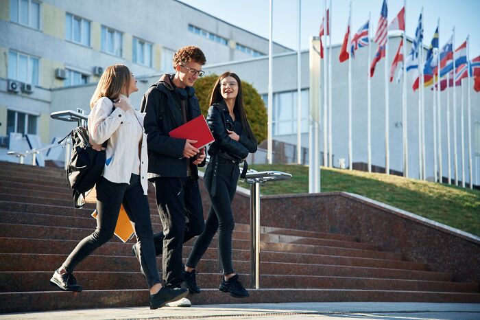 Three young people walking outside a building decorated with multiple flags, illustrating Americans finding a loophole.