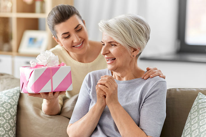 Grandma happily receiving a gift at a baby shower, celebrating her new status with family and friends.