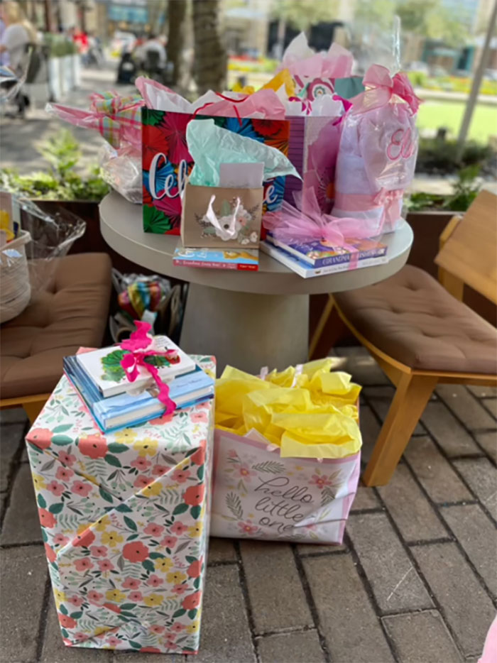Table with colorful gift bags and wrapped presents at a grandma baby shower celebrating her new status outdoors.