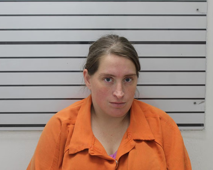 Woman in an orange prison uniform posing for a mugshot after arrest related to stepfather and 11-year-old girl case